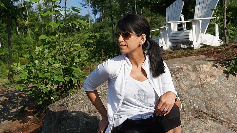 Photo of Dr. Soania Mathur sitting outdoors on a large rock